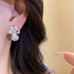Primo piano di eleganti orecchini a lobo a fiore in oro 18k con perla e zircone