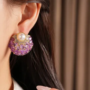 Détail d'une boucle d'oreille vintage avec perle et pierres violettes sur un mannequin