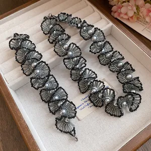 Elegant pearl beaded necklace with intricate black and silver fan-shaped lace details.