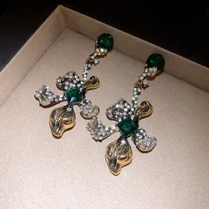 Detail view of vintage gold-tone earrings with emerald green stones and clear crystals