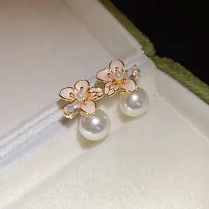 Dettaglio ravvicinato di eleganti orecchini a lobo a fiore placcati oro 18k con perle