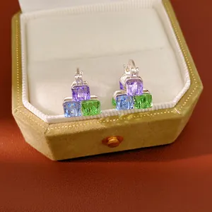 Close-up of colorful geometric square glass earrings inside an elegant green jewelry box