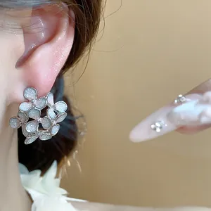 Macro view of delicate flower enamel earrings worn on an ear showing fine details.