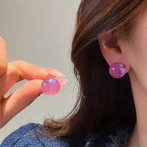 Close-up detail of elegant translucent purple resin round stud earrings worn on ear