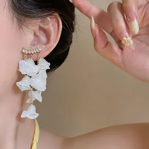 Detail of summer style zircon earrings featuring delicate white chiffon flower petal tassels