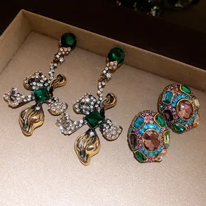 Close-up of vintage jewelry set featuring green stone drop earrings and colorful studs