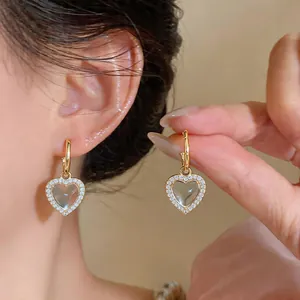 Detailopname van elegante gouden hartvormige oorbellen met hars en zirkonia's