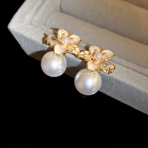 Dettaglio macro di eleganti orecchini a fiore in smalto con perle bianche