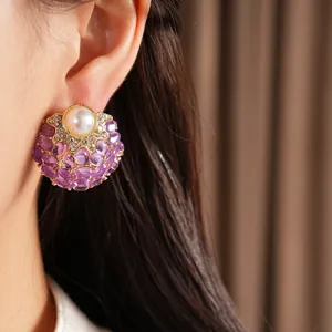 Gros plan d'une boucle d'oreille vintage avec perle et pierres violettes sur l'oreille
