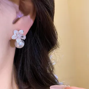 Primo piano di un orecchino a fiore con perla bianca e centro in zircone scintillante