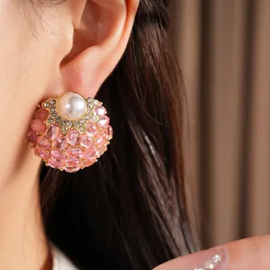 Gros plan détaillé de boucles d'oreilles vintage en résine rose et perles avec strass.