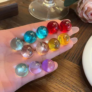 Hand holding a variety of colorful translucent round resin stud earrings in detail