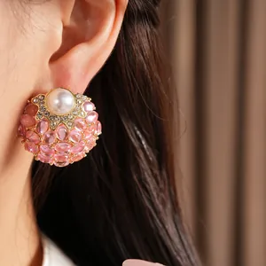 Vue macro détaillée d'une boucle d'oreille vintage avec gemme rose et perle sur l'oreille.