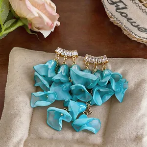Detail of summer chiffon flower tassel earrings with sparkling zircon studs on cushion.