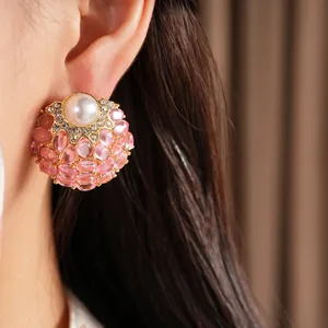 Détail de boucles d'oreilles vintage en perles avec pierres roses et monture dorée