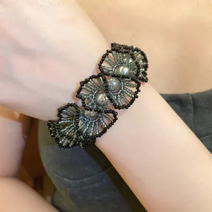 Detail view of a handcrafted black and grey beaded lace bracelet with pearl accents.