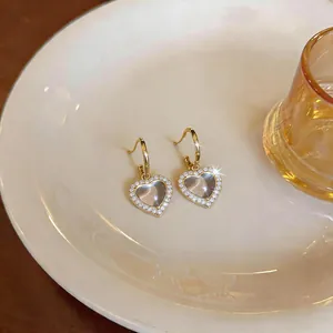 Elegante hartvormige hars oorbellen met zirkonia-rand gepresenteerd op een wit bord