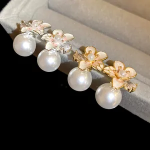 Dettaglio di eleganti orecchini a fiore placcati oro e argento con perle