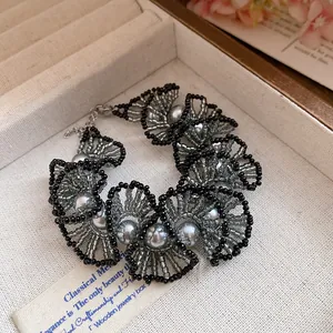 Detailed view of the handcrafted lace-pattern beaded necklace with grey pearls.