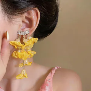 Macro detail of elegant yellow chiffon flower tassel earrings with zircon accents