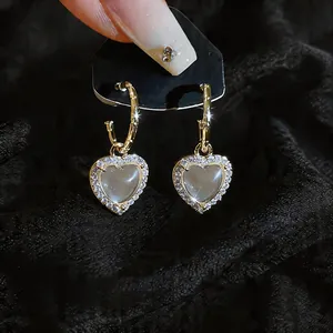 Detailopname van elegante hartvormige oorbellen met hars en schitterende zirkonia. (83 chars)