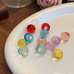 Detailed shot of multi-colored translucent round resin stud earrings on a white plate