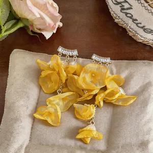 Macro view of delicate yellow chiffon flower tassel earrings with sparkling zircon studs.