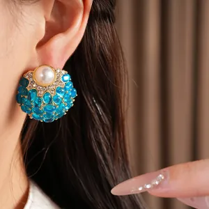 Gros plan de boucles d'oreilles vintage avec perle et pierres cabochons bleues sur modèle.