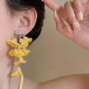 Close-up detail of yellow chiffon flower tassel earrings with zircons on model ear