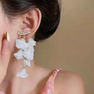 Detail of elegant white chiffon petal tassel earrings with zircon studs on model