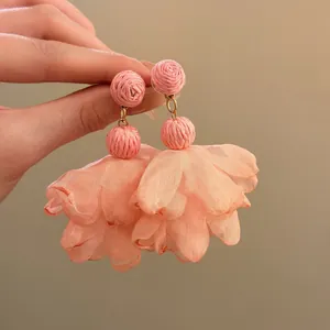 Detail view of handmade pink raffia and chiffon flower petal drop earrings for vacation