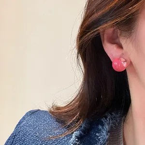 Detailed shot of a minimalist pink resin round stud earring worn on model's ear