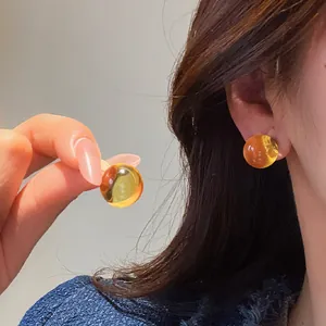 Close-up of minimalist round resin stud earrings in amber yellow finish.