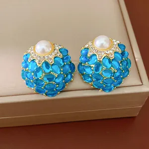 Détail de boucles d'oreilles vintage en or avec perle centrale et pierres bleues