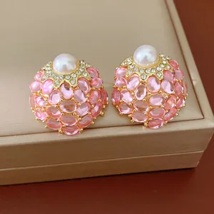Gros plan de boucles d'oreilles vintage roses avec perles et strass brillants.