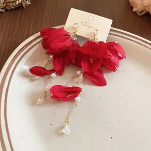 Detailed macro shot of red chiffon flower dangle earrings on a cream display card