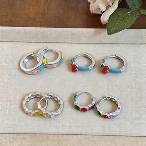 Variety of colorful drip oil enamel hoop earrings with heart, cherry, and smiley patterns.