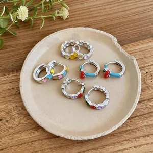 Detail shot of colorful enamel hoop earrings with heart, smile, and cherry motifs
