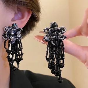 Detailed view of handmade black beaded flower earrings with elegant long tassels