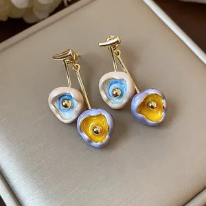 Macro view of handmade colorful enamel flower drop earrings on luxury jewelry pad