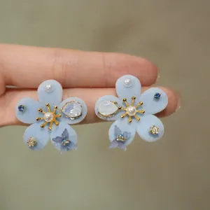 Close-up of light blue flocked flower earrings with pearls and butterfly charms
