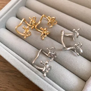 Macro view of minimalist gold and silver double-layer bow ear cuffs in a jewelry organizer