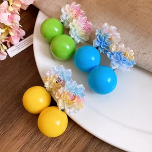 Detailed macro view of colorful resin flower and round ball stud earrings in sweet vacation style