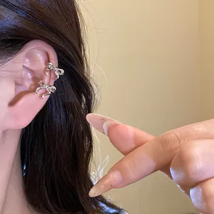 Close-up of stylish silver bow ear cuffs worn on a model's ear for detail