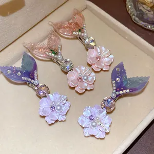 Close-up of mermaid tail hair clips with pearls and rhinestones in jewelry box.