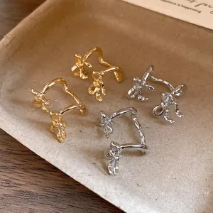 Close-up of elegant double-layered bowtie ear cuffs in gold and silver finishes