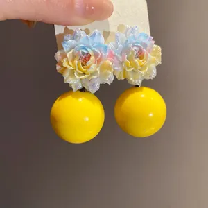 Close-up of resin floral earrings with yellow spherical drops and shimmer