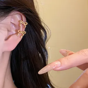 Detailed macro shot of elegant golden bow-shaped ear cuffs worn on the model's ear