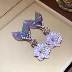 Close-up of mermaid tail hair clips with pearls, rhinestones, and lavender flowers