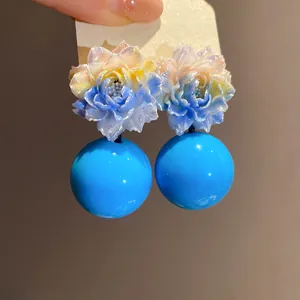Macro detail of sweet floral resin earrings featuring vibrant blue round bead drops.